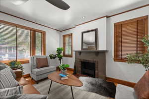 Living area with wood finished floors, ornamental molding, a brick fireplace, ceiling fan, and recessed lighting