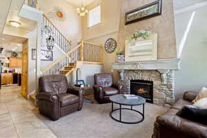 Living room with a chandelier, stairs, a fireplace, and a towering ceiling