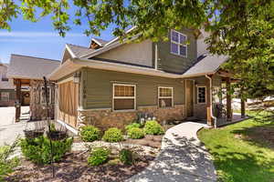 View of front of home featuring stone siding and roof with shingles