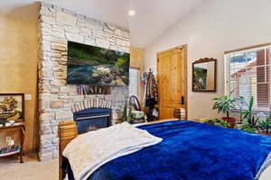 Bedroom featuring lofted ceiling, a fireplace, and carpet