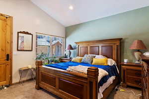 Bedroom with light carpet and high vaulted ceiling