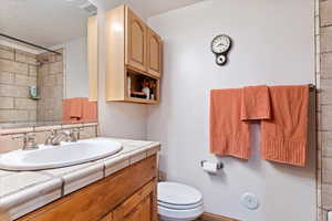 Bathroom featuring vanity, a tile shower, and a textured ceiling