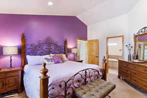 Bedroom with light colored carpet, high vaulted ceiling, and ensuite bathroom