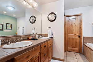Bathroom featuring double vanity, tiled tub, and tile patterned floors