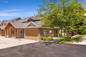 View of front facade featuring stone siding, asphalt driveway, a garage, and a shingled roof