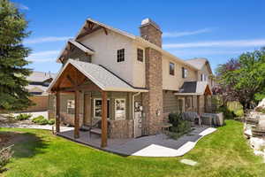Rear view of property with a chimney, stone siding, roof with shingles, and stucco siding
