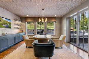 Dining space with a chandelier, wood finished floors, and bar with sink