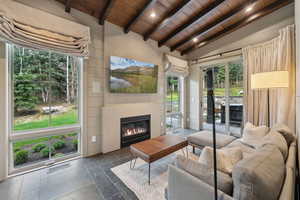 Living area featuring wood ceiling, a glass covered fireplace, stone tile floors, and recessed lighting
