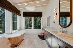 Bathroom featuring healthy amount of natural light, vanity, wooden ceiling, a freestanding bath, and a chandelier