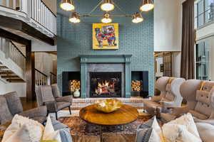 Living room with a towering ceiling, stairway, a fireplace, and wood finished floors