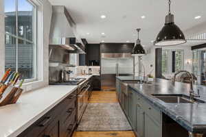 Kitchen with high end appliances, island range hood, decorative backsplash, healthy amount of natural light, and recessed lighting