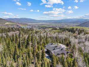 Aerial view of property and surrounding area featuring a mountain backdrop and a heavily wooded area