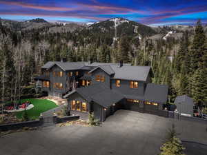 View of front of property featuring a mountain view, a forest view, a garage, driveway, and a chimney
