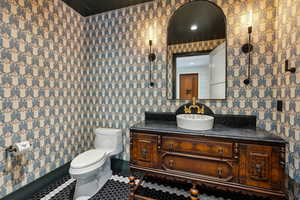 Half bath with vanity, wallpapered walls, and tile patterned flooring