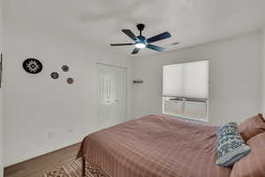 Bedroom with wood finished floors, a ceiling fan, a closet, and a textured ceiling