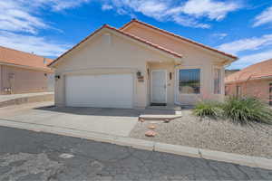 Mediterranean / spanish home featuring driveway, an attached garage, stucco siding, and a tile roof