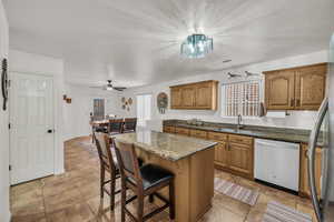 Kitchen with stainless steel appliances, dark stone counters, brown cabinets, a kitchen island, and a textured ceiling