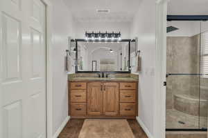 Bathroom with a stall shower, vanity, and dark tile patterned flooring