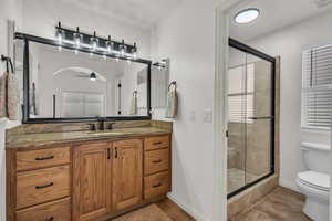 Bathroom with a shower stall, vanity, a ceiling fan, and light tile patterned floors
