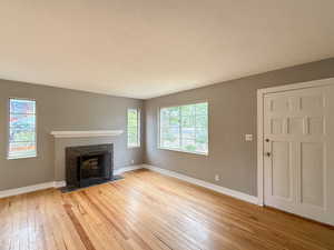Unfurnished living room featuring light wood finished floors and a tiled fireplace