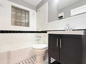 Full bathroom with tile walls, shower / washtub combination, and vanity