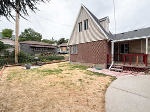 View of side of home featuring brick siding, a lawn, a deck, and a patio area