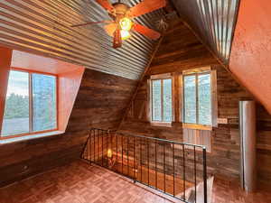 Bonus room with wooden walls, vaulted ceiling, and a ceiling fan