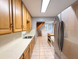 Kitchen featuring freestanding refrigerator, light countertops, light tile patterned flooring, and white range oven