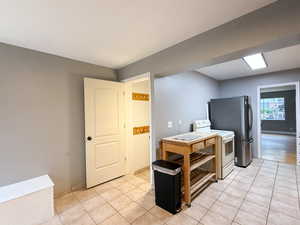 Kitchen featuring washer / dryer, white range with electric stovetop, freestanding refrigerator, and light tile patterned floors