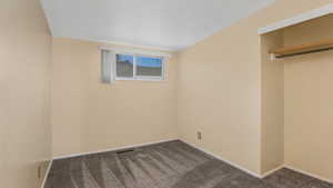 Unfurnished bedroom with dark carpet and baseboards