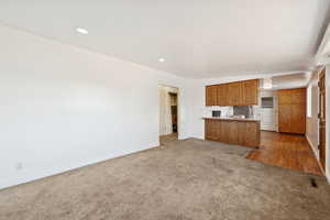 Kitchen with brown cabinets, light carpet, open floor plan, a peninsula, and recessed lighting