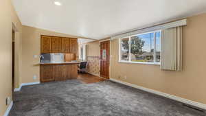 Kitchen with dark carpet, brown cabinets, open floor plan, a peninsula, and recessed lighting