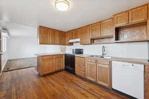 Kitchen featuring dishwasher, electric range, light countertops, dark wood finished floors, and a peninsula