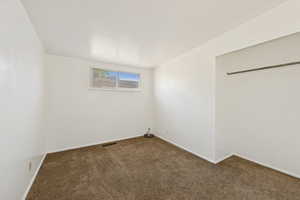 Unfurnished bedroom featuring dark colored carpet and a closet