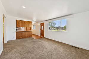 Unfurnished living room featuring carpet and vaulted ceiling