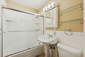Full bathroom with shower / bath combination with glass door and toilet