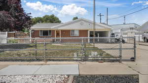 Ranch-style house featuring brick siding, a fenced front yard, and covered porch