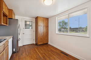 Kitchen featuring brown cabinets, dark wood-style floors, light countertops, and dishwasher