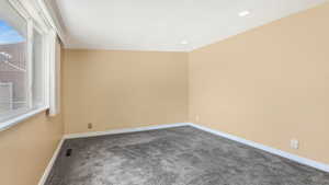 Empty room featuring dark colored carpet and recessed lighting