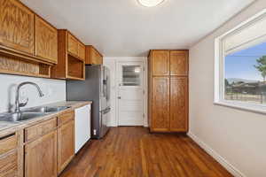 Kitchen featuring brown cabinets, dark wood-type flooring, light countertops, dishwasher, and open shelves