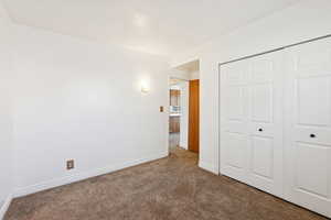 Unfurnished bedroom with dark colored carpet and a closet