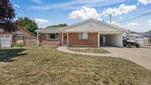 Single story home featuring brick siding, driveway, and an attached carport