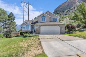 View of front of home featuring a garage, concrete driveway, a front lawn, stucco siding, and a mountain view