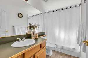 Full bathroom featuring vanity, wood finished floors, and shower / bathtub combination with curtain
