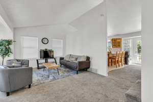 Carpeted living area featuring lofted ceiling and baseboards