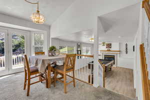 Dining space featuring vaulted ceiling, a chandelier, a tiled fireplace, and wood finished floors