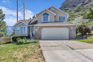Traditional-style house featuring a front yard, concrete driveway, a garage, a mountain view, and stucco siding