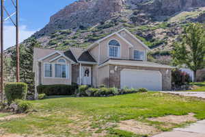 Tri-level home with a front yard, a garage, a mountain view, driveway, and brick siding