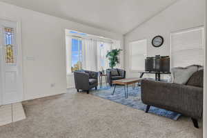 Living room with carpet floors, vaulted ceiling, and healthy amount of natural light