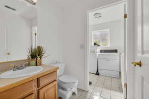 Bathroom with washer / dryer, vanity, and tile patterned floors